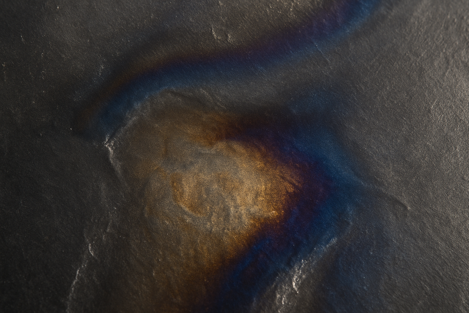 a dark gray metal with some discoloration or glazing from heat, as if it has been heated or sanded